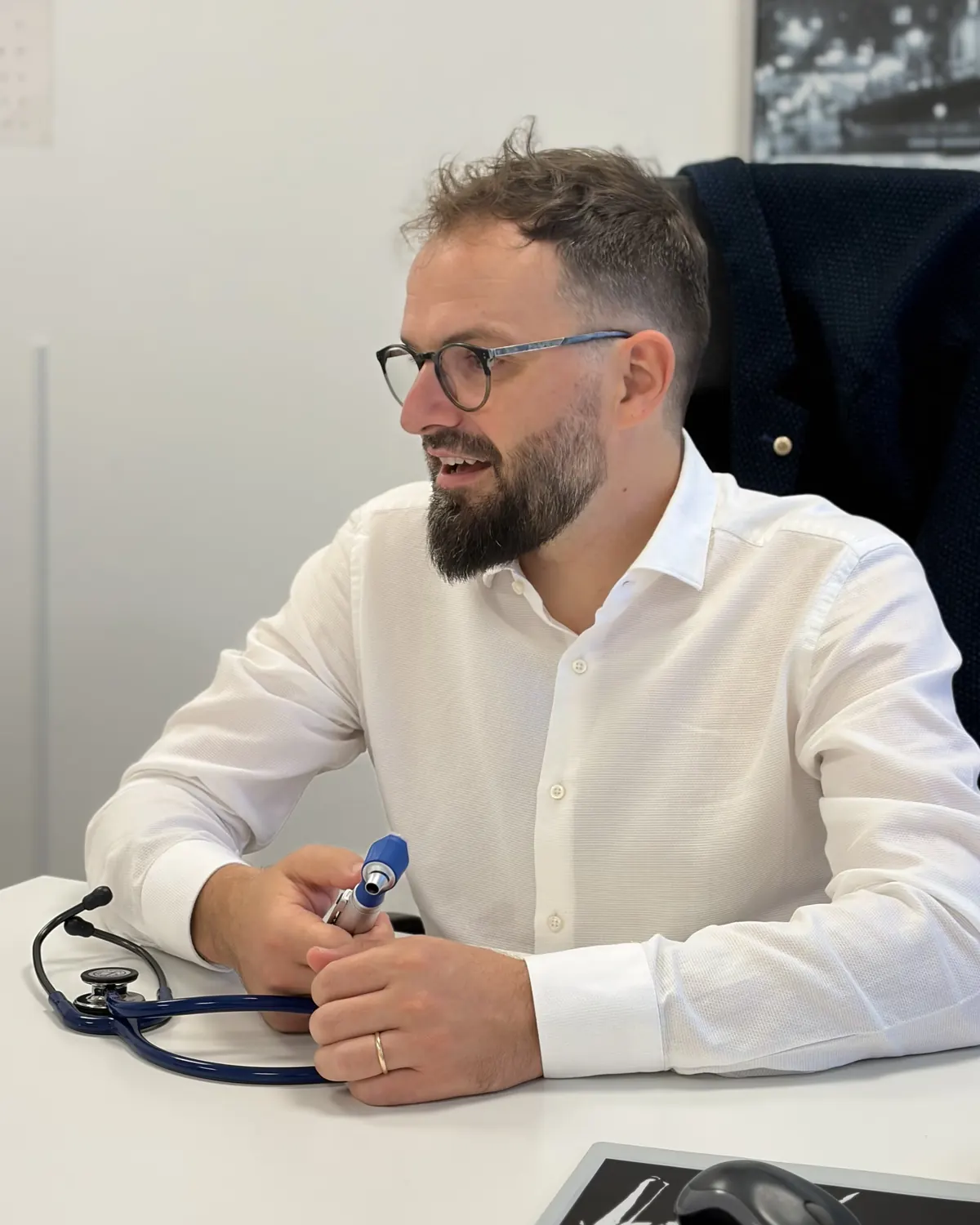 Il dott. Davide Cucchiaro alla scrivania dello studio, con fonendoscopio e otoscopio